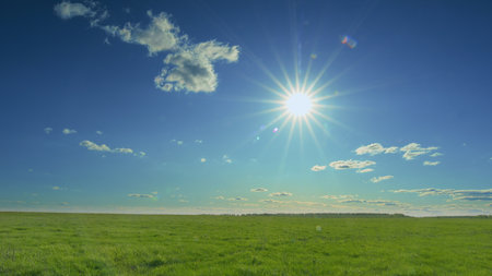A Beautiful Sunny Landscape featuring Clear Blue Skies and Gorgeous Vibrant Green Grass Time lapse.の写真素材