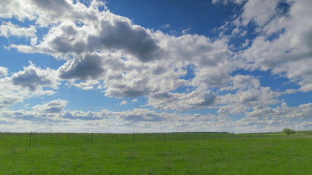 The Serene Green Fields Stretch Elegantly Underneath a Stunningly Beautiful Cloudy Sky Time lapse.の写真素材