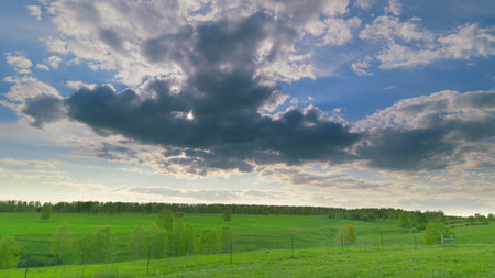 A Serene and Picturesque Green Landscape Set Beneath Dramatic and Beautiful Clouds Above Time lapse.の写真素材