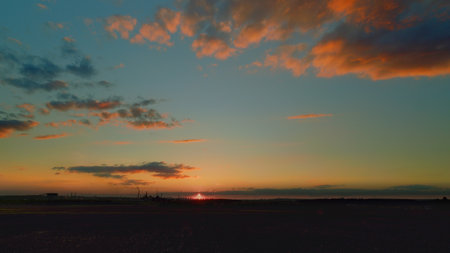 A Stunning Sunset Over a Calm Horizon Accompanied by Colorful and Dramatic Cloudsの写真素材