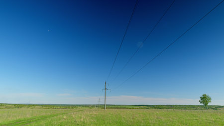 A Vast Expansive Open Landscape Featuring Power Lines Beneath a Bright Clear Sky Aboveの写真素材