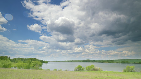 The picturesque and lush river landscape stretches vividly, set against a dynamic cloudy sky Time lapse.の写真素材