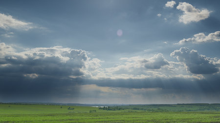 The tranquil sky stretches above the lush, green fields, creating a breathtaking view of nature Time lapse.の写真素材