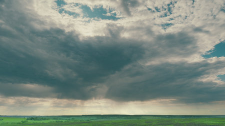 Dramatic Cloudscape Over Lush Green Fields Showcasing Natures Breathtaking Beauty and Serenity Time lapse.の写真素材