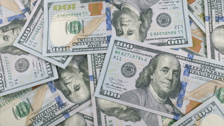 Piles of neatly arranged Hundred Dollar Bills spread out attractively on a table surfaceの写真素材