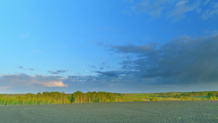 A breathtaking scenic landscape showcasing the beauty of rolling fields beneath a dramatic sky Time lapse.の写真素材