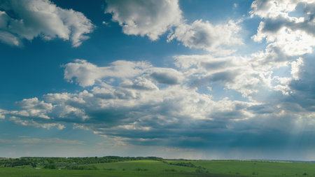 Serene and Beautiful Clouds Floating Over a Lush Green Landscape During Bright Daylight Time lapse.の写真素材