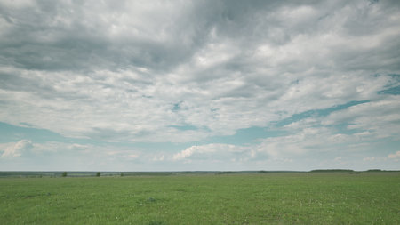 A Vast Green Field Sprawling Under a Beautiful Cloudy Sky, Ready to Be Explored, Awaits You Time lapse.の写真素材