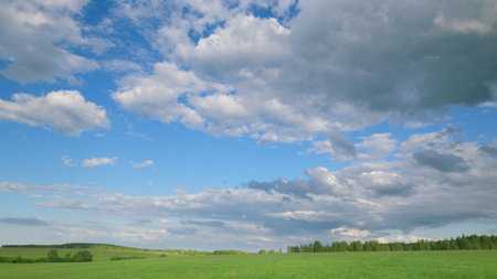 A Vibrant Cloudy Sky Over a Beautiful Green Meadow Landscape That Captivates Natures Essenceの写真素材