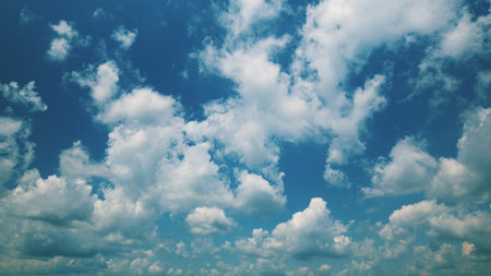 Time lapse. A Beautiful Blue Sky, richly adorned with Fluffy White Clouds that are floating gracefully aboveの写真素材