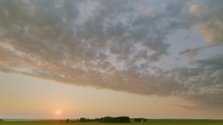 Time lapse. A Stunning Sunrise Gently Lights Up a Beautifully Serene Landscape Under a Gorgeous, Cloudy Skyの写真素材