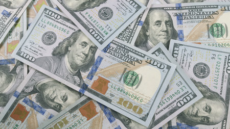 A detailed closeup view showcasing numerous hundred dollar bills scattered across a flat surface...