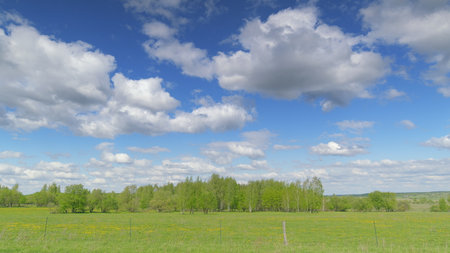 A Scenic Green Pasture Nestled Under a Beautifully Cloudy Blue Sky, Full of Life and Color Time lapse.の写真素材