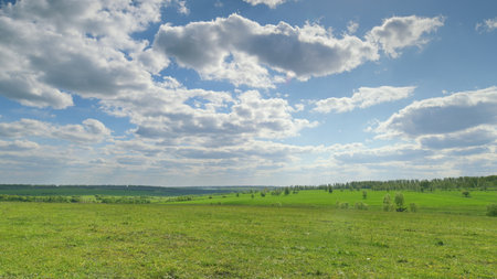 A Vast Green Landscape Stretching Under a Bright Blue Sky Filled with Soft, Fluffy Clouds Time lapse.の写真素材