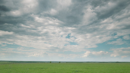A Serene Landscape Featuring a Cloudy Sky Above Expansive Green Fields All Around Time lapse.の写真素材