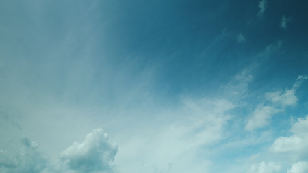 Time lapse. A Beautiful Sky with Fluffy Clouds Slowly Merging in a Bright Blue Atmosphere Above Usの写真素材