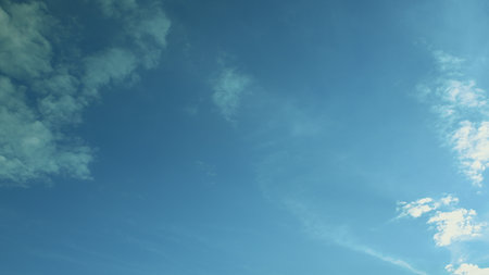 A Crystal Clear Blue Sky Adorned with Soft, Fluffy Clouds Captured on a Gorgeous Sunny Dayの写真素材