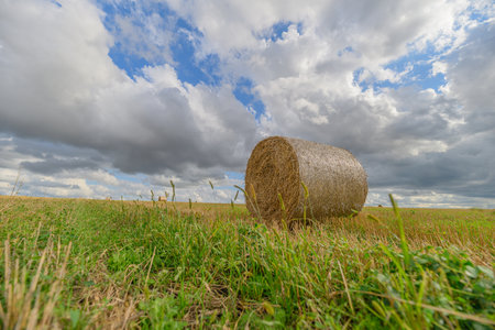 A tranquil and serene landscape featuring a single hay bale set against a dramatic skyの写真素材