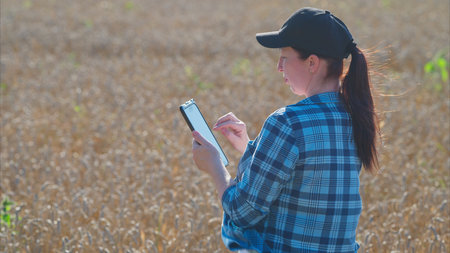 A young woman is actively using her smartphone in a vibrant field full of sunshine