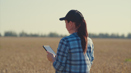 A Young Woman Actively Engaged in Using a Tablet While Standing in a Beautiful Field