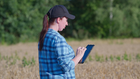 Woman using a tablet for tasks and analysis while working in an agricultural field