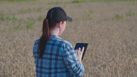 A farm worker utilizing a tablet in the agricultural field for comprehensive data analysisの写真素材