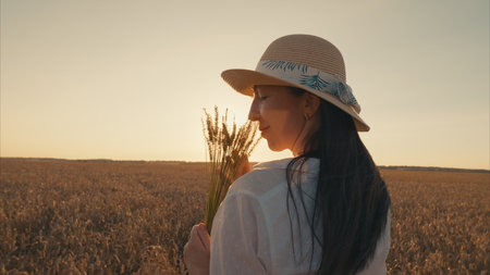 A Serene Woman Standing in a Beautiful Field at Sunset Surrounded by Colorful Flowersの写真素材