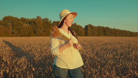 A woman walking proudly in a lush wheat field, joyfully holding the harvest she has gathered