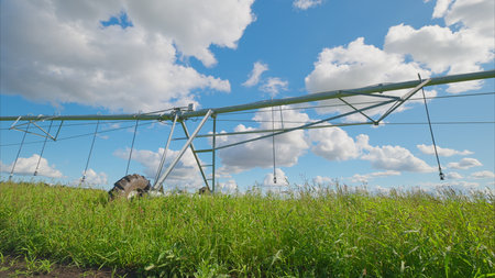Efficient Irrigation System in Agricultural Field Under Beautiful Blue Sky with Clouds Aboveの写真素材