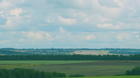 A Serene Landscape Featuring Verdant Fields Under a Beautifully Cloudy Sky Aboveの写真素材