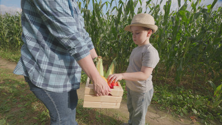 A joyful child exuberantly enjoying an array of fresh produce at the farm with familyの写真素材
