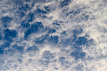 Serene and beautifully patterned cloud formations drift peacefully beneath a bright blue sky