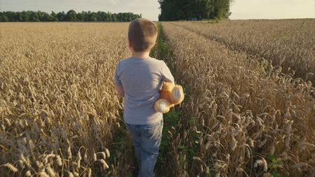 A child joyfully exploring a sunny field filled with golden wheat while holding a toy