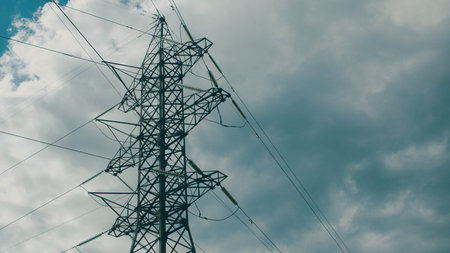 High Tension Power Lines Stand Against a Dramatic Sky, Emphasizing Connectivity and Energyの写真素材
