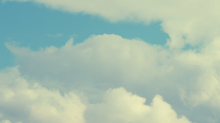 A Serene Sky adorned with Fluffy White Clouds floating gently across the vast blue canvas