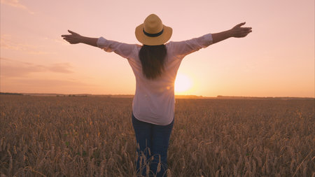 Experiencing Freedom in Nature Embracing the Beautiful Sunset in a Golden Wheat Fieldの写真素材