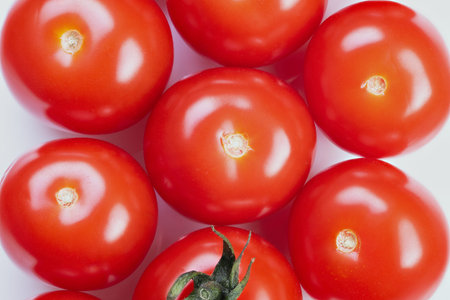 Bright red cherry tomatoes on white background, glossy skin, single green stem, natural highlights,...