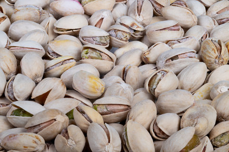 Crunchy salted pistachios with green kernels and beige shells. Closeup of salted pistachios...