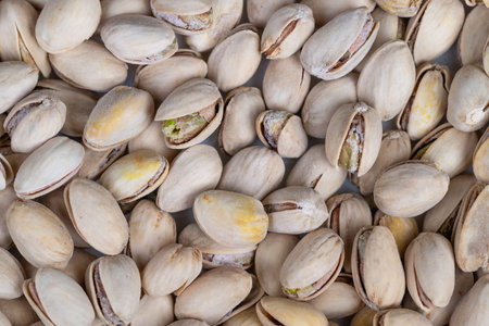 Closeup pistachio shells piled tightly, beige shells with green kernel hints, soft lighting...