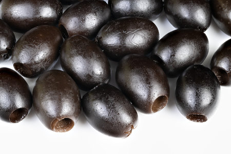 Closeup cured black olives arranged in tight cluster, glossy skins, culinary vibe suggesting salad or antipasto prep, warm highlights and natural imperfections visibleの写真素材