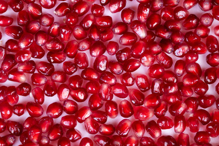 Bright pomegranate seeds arranged in festive pattern, seasonal decoration concept for holiday recipes, rich crimson tiles create eyecatching background and bold color contrastの写真素材