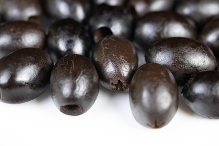 Closeup black olives arranged tightly with visible pits, wet sheen, reflective highlights, natural dark tones, kitchen prep mood, versatile topping for salad and pizzaの写真素材
