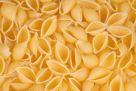Flatlay composition of yellow pasta shells with crisp edges and even colors. Geometric pasta shell...
