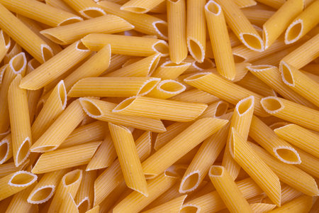 Smooth textured penne pasta background, Detailed image of ridged penne pasta featuring warm hues and...
