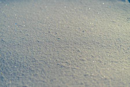 Calm snow texture with soft blue tint, fine crystal facets catching daylight, wide shallow plane...