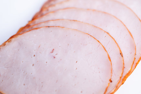 Charcuterie ham slices layered for board assembly, delicate curves and seasoned edge add visual...