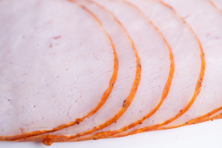 Deli production sliced ham ready for packing, consistent portioning and seasoned rim emphasize...