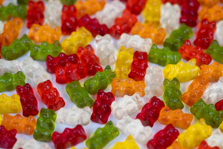 Colorful candy scene. Multicolored gummy bears focused tightly against white background. Sharp macro...