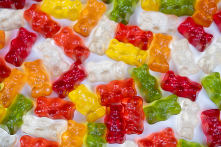 Brightly hued gummy bears form artistic mosaic surface. An array of multicolored gummy bears creates...