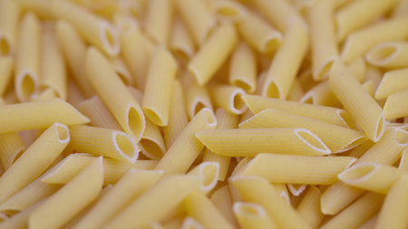 Closeup of uncooked penne, Dense pattern of raw penne with textured semolina surface, Cinematic shot...